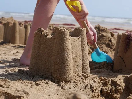 enfant faisant un chateau de sable sur la plage