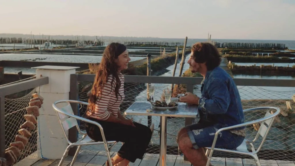 photo d'un couple mangeant un plateau d'huitres au milieu des parcs ostréicoles de fromentine