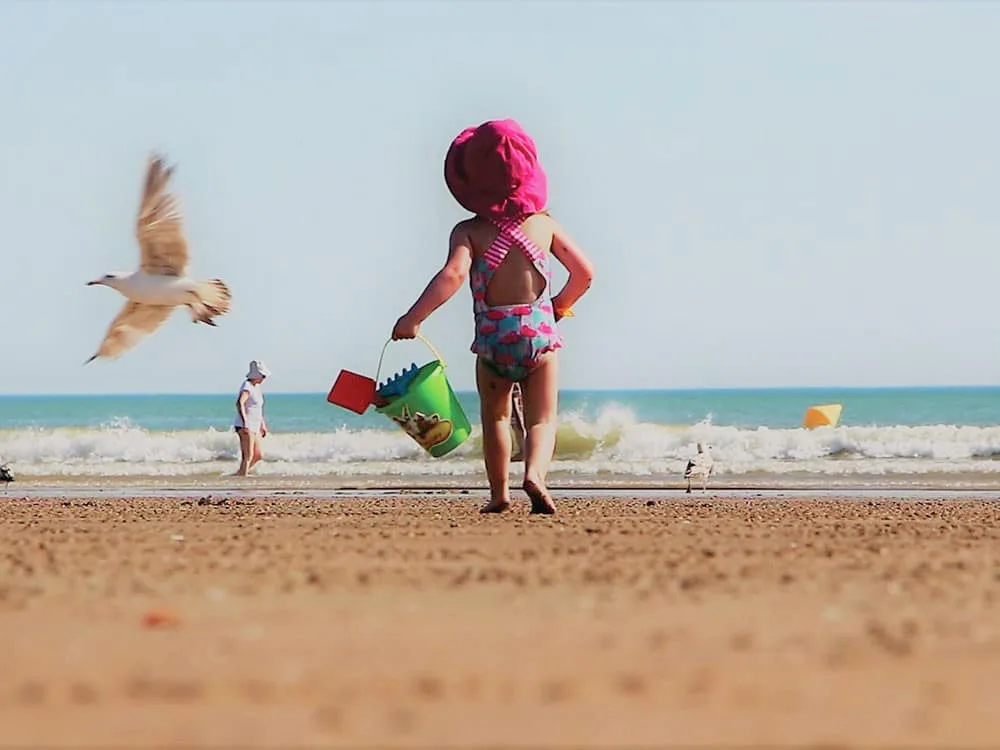 enfants marchant sur la plage avec un saut et un chapeau