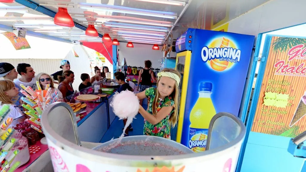 enfant faisant une barbe à papa dans un stand de confiseries