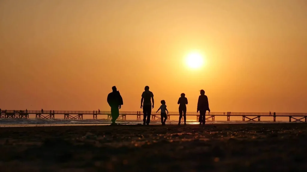 Groupe de personnes marchant sur la plage au coucher du soleil pendant l'événement La Dunaire Montoise