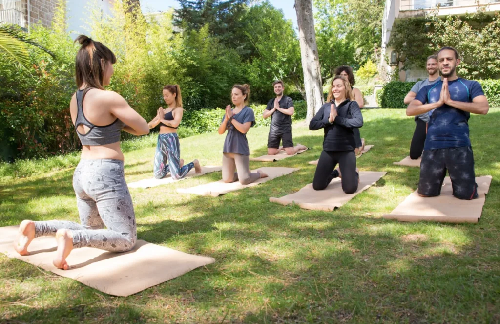 groupe de personnes faisant un cours de yoga dans la forêt