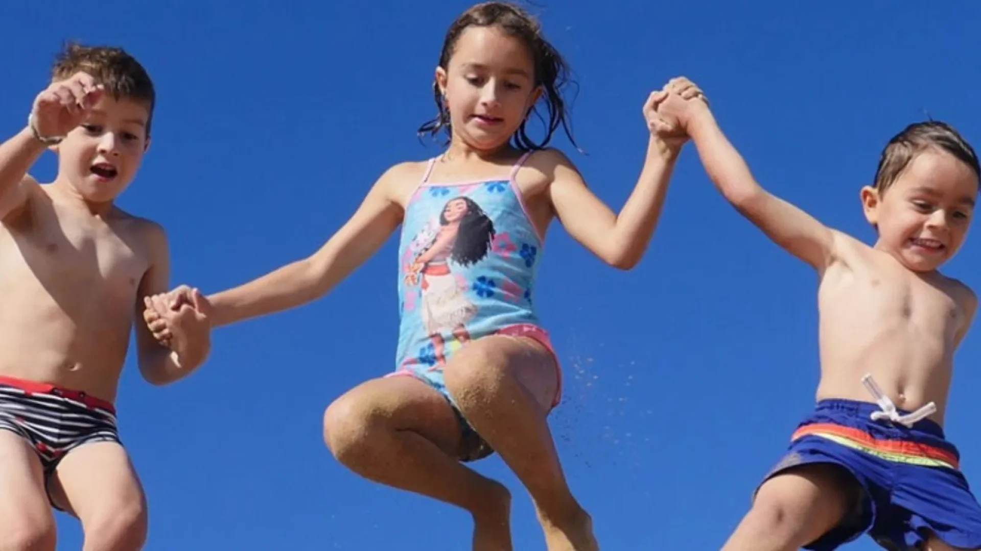 trois enfants sautant dans le sable sur une plage du pays de saint jean de monts