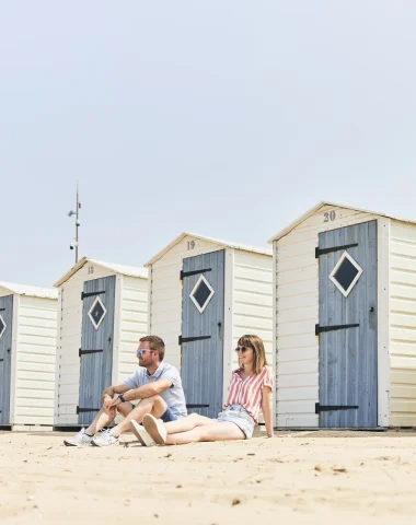 photo d'un couple assis sur la plage devant les cabines de notre dame de monts