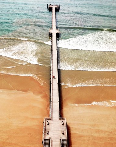 Photo en drone de l'estacade de Saint Jean de Monts. Le sable est orange et il y a des vagues qui donnent du mouvement à la mer.
