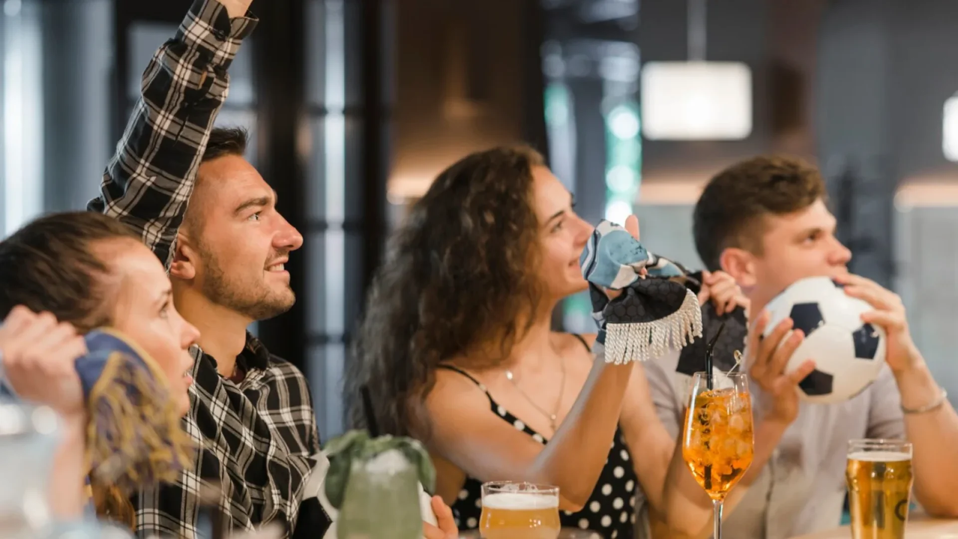 groupe d'amis fans de sport supportant un club dans un bar qui retransmet le sport en direct