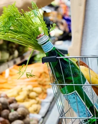 image d'une femme avec un panier qui fait ses courses dans un commerce au Perrier. Elle achète notamment des légumes et de l'eau.
