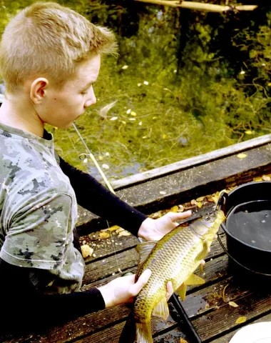 un enfant pêche un gros poisson en eau douce